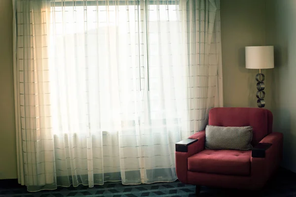 Típica habitación de hotel con sofá rojo y cortina de cierre cálida luz de la mañana retroiluminada — Foto de Stock