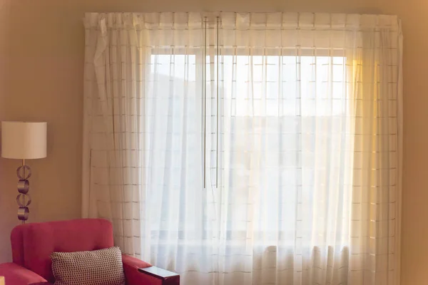 Típica habitación de hotel con sofá rojo y cortina de cierre cálida luz de la mañana retroiluminada — Foto de Stock