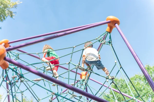 Felfelé néző többnemzetiségű változatos gyerekek mászó kupola játszótér közelében Dallas, Texas, USA — Stock Fotó
