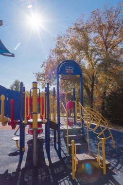 Güneşli sonbahar gününde çocukların oyun parkına giden merdivenler açık mavi gökyüzü ve renkli sonbahar yaprakları. Teksas, Teksas 'ta, Flower Mound' da gölge yelkenli ve kauçuk döşemeli halk parkı.
