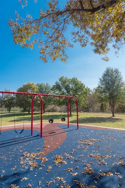在美国德克萨斯州花圃附近的公园里 红色的秋叶和五彩缤纷的落叶在公共游乐场里荡漾 橡胶垫地板上的落叶 — 图库照片