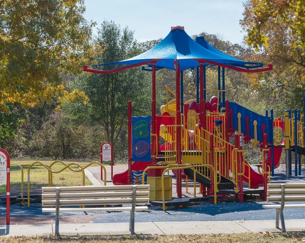Arkadaki iki boş bankta sonbahar yaprakları ile renklendirilmiş oyun parkına bakıyor. Teksas, ABD — Stok fotoğraf