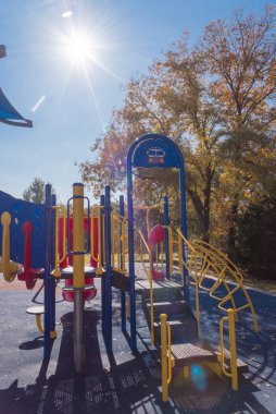 Güneşli sonbahar gününde çocukların oyun parkına yakın çekimde Teksas, ABD 'de güneş patlaması ve düşen yapraklarla.