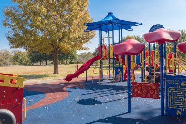 Doğa parkının yanındaki renkli halk parkı. Flower Mound, Teksas, Amerika 'da renkli sonbahar yeşillikleri var. Gölge yelkenli ve kırmızı itfaiye temalı çocuk eğlence ekipmanları.