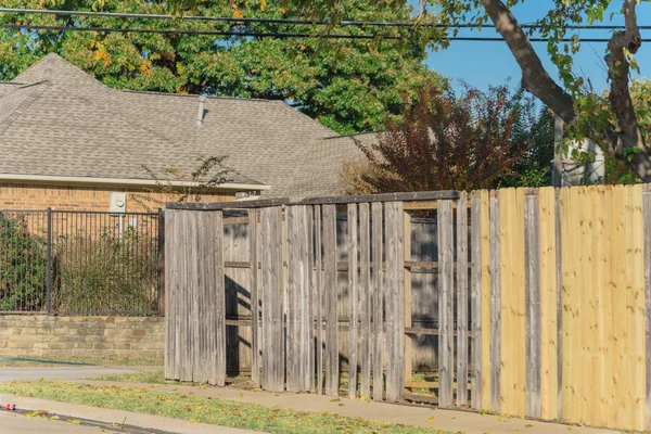 Collapsed aged wooden fence near new lumber boards installation at backyard of residential house in suburban Dallas, Texas, America. Large corner house fence replacement in progress.