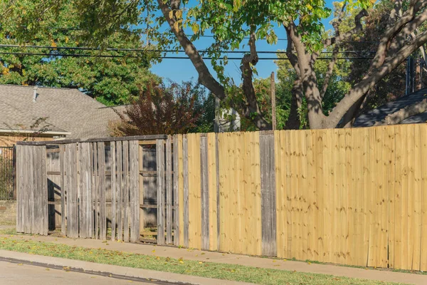 Collapsed aged wooden fence near new lumber boards installation at backyard of residential house in suburban Dallas, Texas, America. Large corner house fence replacement in progress.