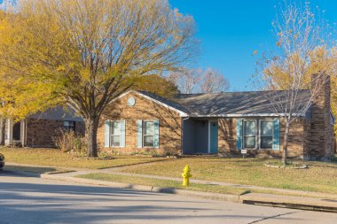 Dallas, Teksas, Amerika 'nın banliyölerinde renkli sonbahar yeşillikleri olan tipik bir banliyö evi. Geniş çimenli ön bahçesi olan bir ev.