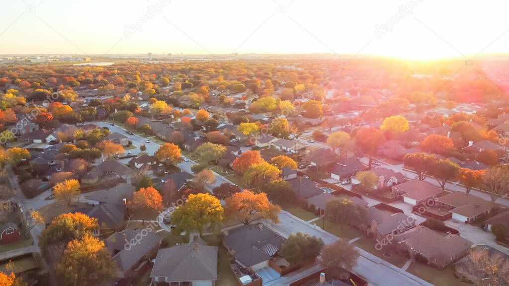 Aerial view residential neighborhood with colorful fall foliage at sunset near Dallas, Texas, America. Top view sprawl subdivision in a master planned community into horizontal line