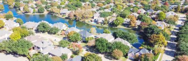 Coppell, Teksas, Amerika 'daki Panorama hava manzaralı göl manzaralı bir mahalle. Güneşli sonbahar gününde renkli sonbahar yeşillikleriyle çevrili en tepedeki evler.