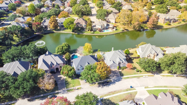 Lakeside houses with water fountain and colorful fall foliage in Coppell, Texas, America. Aerial view upscale residential neighborhood in a sunny autumn day