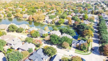 Coppell, Texas, Amerika 'daki göl manzaralı bir semt. Güneşli sonbahar gününde renkli sonbahar yeşillikleriyle çevrili en tepedeki evler.