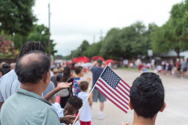 Bağımsızlık Günü Sokak Yürüyüşü 'nde çeşitli insanlar Amerikan bayrağı sallıyor.