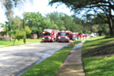 Bulanık soyut görüntülü itfaiye arabaları. Üzerinde parlayan ışıklar var. Dallas, Teksas, Amerika yakınlarında olgunlaşmış ağaçlar var. Banliyödeki yangın musluğundan su dökülmüş..