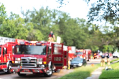 Bulanık manzaralı itfaiyeci. İtfaiye aracının tepesinde yanıp sönen ışıklar ve kaldırımda Dallas, Teksas, Amerika 'nın banliyölerindeki ev yangını.