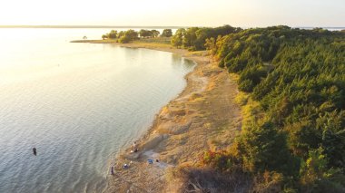 Ticky Creek Parkı 'nda, Princeton, Teksas, Amerika' daki Lavon Gölü 'nün kuzey ucunda balık tutan insanların bulunduğu havadan kumlu kıyı şeridi..