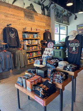 NORTH RICHLAND HILLS, TX, US-OCT 4, 25: Retail section at Black Rifle Coffee Company has hoodies, hanging shirts, stacked coffee bags with themed like AK-47 and Freedom Fuel, rugged, organized layout