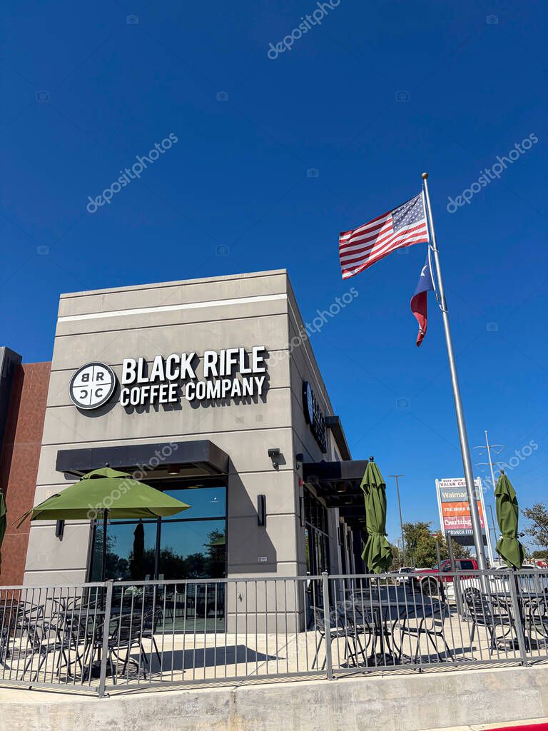 NORTH RICHLAND HILLS, TX, US-OCT 4, 25: Black Rifle Coffee Company Cafe patio with green umbrellas, metal fencing, American and Texas flags, offering shaded seating and welcoming suburban vibe. USA