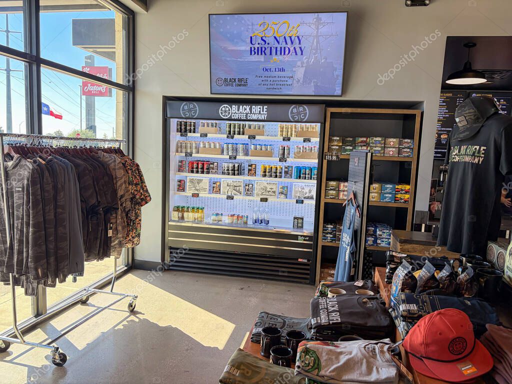 NORTH RICHLAND HILLS, TX, US-OCT 4, 25: Refrigerated stocked canned coffee drinks, flanked by camo jackets, promotional signage for U.S. Navy 250 birthday, blending convenience with patriotic branding