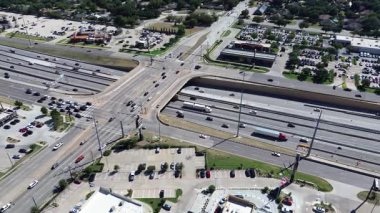 Highway interchange overpass structure, flat-roof restaurant pads, fast food signage, retail stores parking lots, surround traffic lights, feeder roads, mixed use zones in North Richland Hills