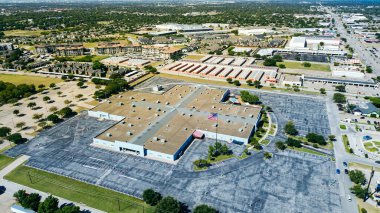 Industrial building flat roof HVAC units, unoccupied parking lot, adjacent storage facility, apartment complex, suburban homes near NE Loop 820 highway-front retail pads, North Richland Hills, TX. USA