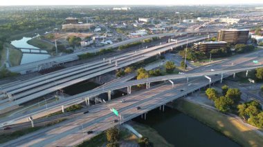 Stacked highway interchange spans Trinity River, flanked by office buildings, campus zones, rail tracks, industrial corridors. Green buffer, paved trails reflect Fort Worth layered urban planning