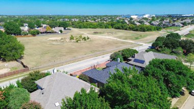 Suburban street in North Richland Hills, Texas, dividing two story upscale residential homes from large vacant tract land natural terrain, trees, future development potential suburbs Ft. Worth. USA