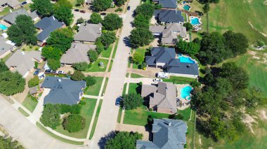 Upscale suburban homes in North Richland Hills, Texas, featuring backyard pools, manicured lawns, mature trees, recreational RV park along clean, tree-lined residential driveway, suburb Ft. Worth. USA