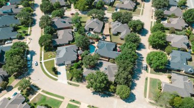 Two-story homes with solar rooftops in suburban neighborhood in North Richland Hills, Texas, central tree-lined street subdivision with manicured lawns, pools and consistent architectural rhythm. USA