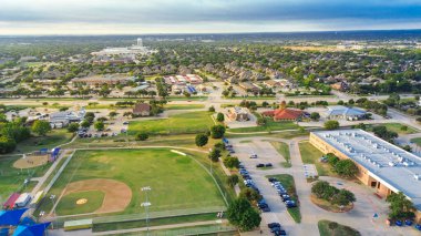 Bitişiğinde beyzbol sahası, futbol sahası, çocuk parkı olan okul kampüsü. Mavi ve kırmızı çatılı pavyonlar, geniş yollar, kilise, evler Highland Village 'da birbirine bağlı banliyö manzarası oluşturur. ABD
