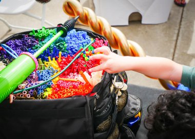 Yan gören çocuk, içi düzgün düzenlenmiş balonlarla dolu, bükülmüş balonla hazır siyah çantaya bakıyor. Beyaz sandalyeler, Dallas, Teksas 'ta balon topluluğunun faaliyet göstermesini öneriyor. ABD