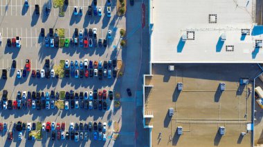 Büyük Lewisville perakende parkında gaz ve elektrikli araçlarla yoğun park, ön girişlere yakın ADA alanları, HVAC üniteli düz çatı, ve aydınlıktan karanlığa doğru asfalt kaplama, Texas. ABD