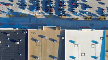 Düz çatı perakende binası, koyu-aydınlık kaplamaları, çatısı HVAC kümeleri, ön tarafa bakan park yerleri. Asfalt varyasyonu, Lewisville, TX gibi ticari alanlarda termal ve bakım bölgelerini yansıtıyor. ABD