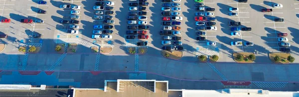 Lewisville perakende parkında gaz, elektrikli araçlar, ön girişlere yakın ADA alanları, düz çatı HVAC birimleri ve aydınlıktan karanlığa doğru asfalt kaplamalarla dolu panorama manzaralı yoğun bir park yeri. ABD