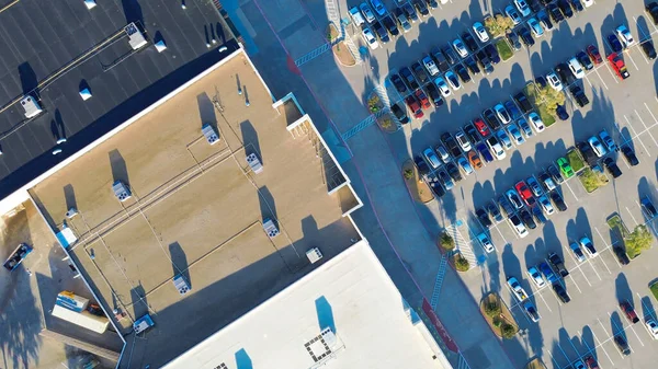 Düz çatılı HVAC üniteleri ve ön cephe parkına sahip geniş perakende şeridi boyunca açılı manzara. Gaz ve elektrikli araçlar, ADA bölgeleri, peyzaj araçları banliyö planlama verimliliği, TX gösteriyor. ABD