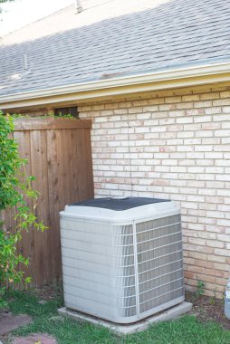 Kiremitli çatı, çatı kiremitleri ve merkezi havalandırma ünitesi olan banliyö evinin köşesi. Coppell, Teksas 'ta beton tuğla kaplama ve ahşap çitlere kurulmuş. Kırmızı basamaklar, sarmaşık bitkisi. ABD