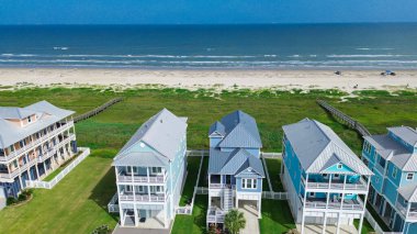 Metal çatıları ve balkonları olan yüksek yazlık evler Güney Sahili, Galveston kıyısı, kıyı şeridine ulaşmak için özel tahta kaldırımlar, harmanlanmış evler ve doğa. ABD