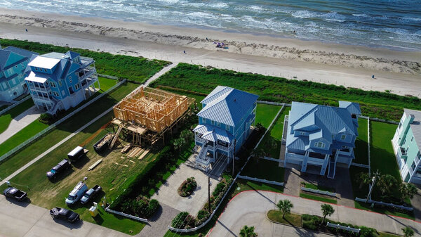 Постановки зоны в Солнечном Берегу, Галвестоне, Техасе, строительных материалах, окаймлённых домах на сваях, действующих экипажах. Переходная фаза развития прибрежной зоны с подтоплением инженерных сооружений вблизи готовых домов. США