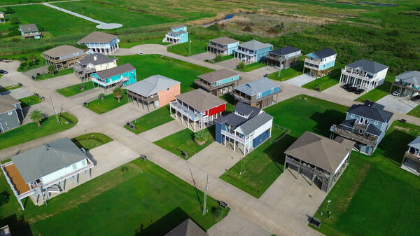 Красочные прибрежные дома возле Beach Boyt отличаются яркой архитектурой помех, травянистыми дворами и припаркованными автомобилями, что отражает сезонный образ жизни и сознательный к наводнениям дизайн в районе Мексиканского залива в Техасе. США