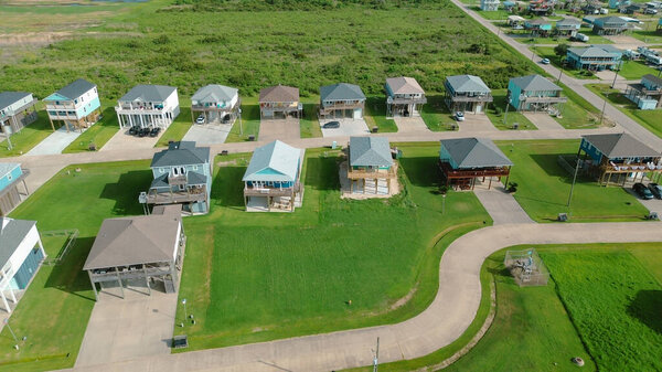 Изогнутая жилая улица рядом с высотными домами с проезжими частями, газонами и пустующими землями, иллюстрирующая интеграцию инфраструктуры в противопаводковую, пляжно-соседнюю жилую сеть, Порт Боливар. США