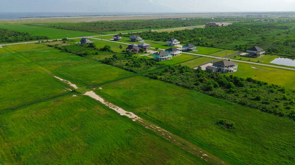 Scattered homes with green lawns and paved roads stretch towards Beach Boyt, offering peaceful semi-rural setting, vacation rental with water views, low-density development in Port Bolivar, Texas. США