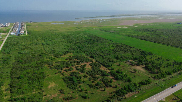 Огромные травянистые пустыри возле разбросанных пляжных домов с каналом, асфальтированные дороги, ведущие к пляжному Бойту, полусельская местность, аренда отпусков в районе Порт-Боливар, штат Техас. США
