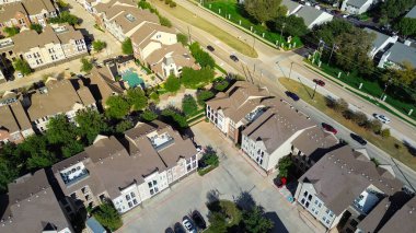 Kahverengi çatılı, bej kaplamalı, şebeke benzeri apartman dairesi, çitli havuz etrafında şezlonglar. Otoparklar, garaj yolları, ağaçların oluşturduğu yollar düzenli yerleşim yeri, Çiçek Tepesi, Teksas. ABD