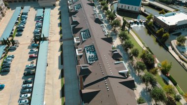 Kahverengi çatılı uzun binalar, sıra sıra havalandırma üniteleri. Bitişik park yerleri, peyzaj bölgeleri, kanal kenarındaki yeşillikler altyapı görüşünü arttırıyor, Flower Mound, Texas. ABD