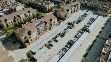 Dar apartmanlar, geniş park yerleri, metal otoparklar. Kahverengi çatılar, bej ön cepheler, araba-merkezli kiralık araç ayak izleri, Flower Mound, Texas. ABD