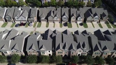 Teksas, Flower Mound 'da iki katlı üniformalı evler. Dar arsalara yerleştirilmiş çatılar, tuğla cepheler, garaj yolları ve küçük çimenler. Yoğun yerleşim banliyö planlama kesinliğini vurguluyor