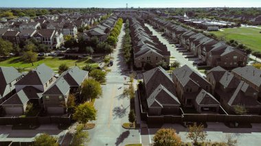 Eğri yolu, çalıları, boş otlağı olan peyzaj arazisi merkez ağaçlı cadde boyunca sıralanmış çatı katları, kaldırımlar, yapılandırılmış yerleşime yumuşaklık, çiçek tepeciği, TX 'e görsel ekliyor. ABD