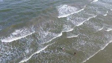 Vietnamlı çocuklar Galveston Porretto Sahili sahil şeridinde huzur içinde sörf yapıyorlar. İstikrarlı dalga çizgileri, kumlu dokular, Teksas 'ın popüler tatil beldelerinde doğal körfez ambiyansı kıyı tatili.