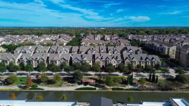 Nehir kenarındaki banliyö evlerinin arka planında düzenli sıralar, tuğla cephe, dar arazi, düz çatı ticari bina, konut yoğunluğu, karma kullanım alanı, Flower Mound, TX. ABD