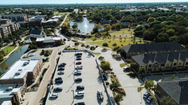 Çatı katındaki otopark, çeşme, şehir evleri, apartman kompleksi, nehir kenarındaki restoran ve peyzaj yolları, eğlence ve toplum nişanı, Flower Mound, TX. ABD