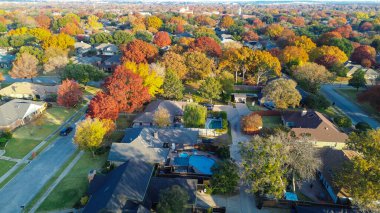 Geniş açık çimenlik alan geçişleri kırmızı, turuncu, altın yapraklı canlı ağaç tepe örtüsüne sessiz Coppell yerleşim bölgesi. Karşıtlık olarak mevsimsel değişiklikler ve banliyö mekansal planlaması vurgulanıyor. ABD